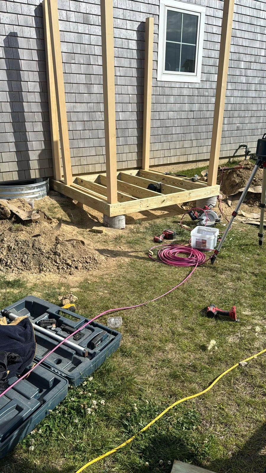 Exterior deck stairs under construction beside a stone wall